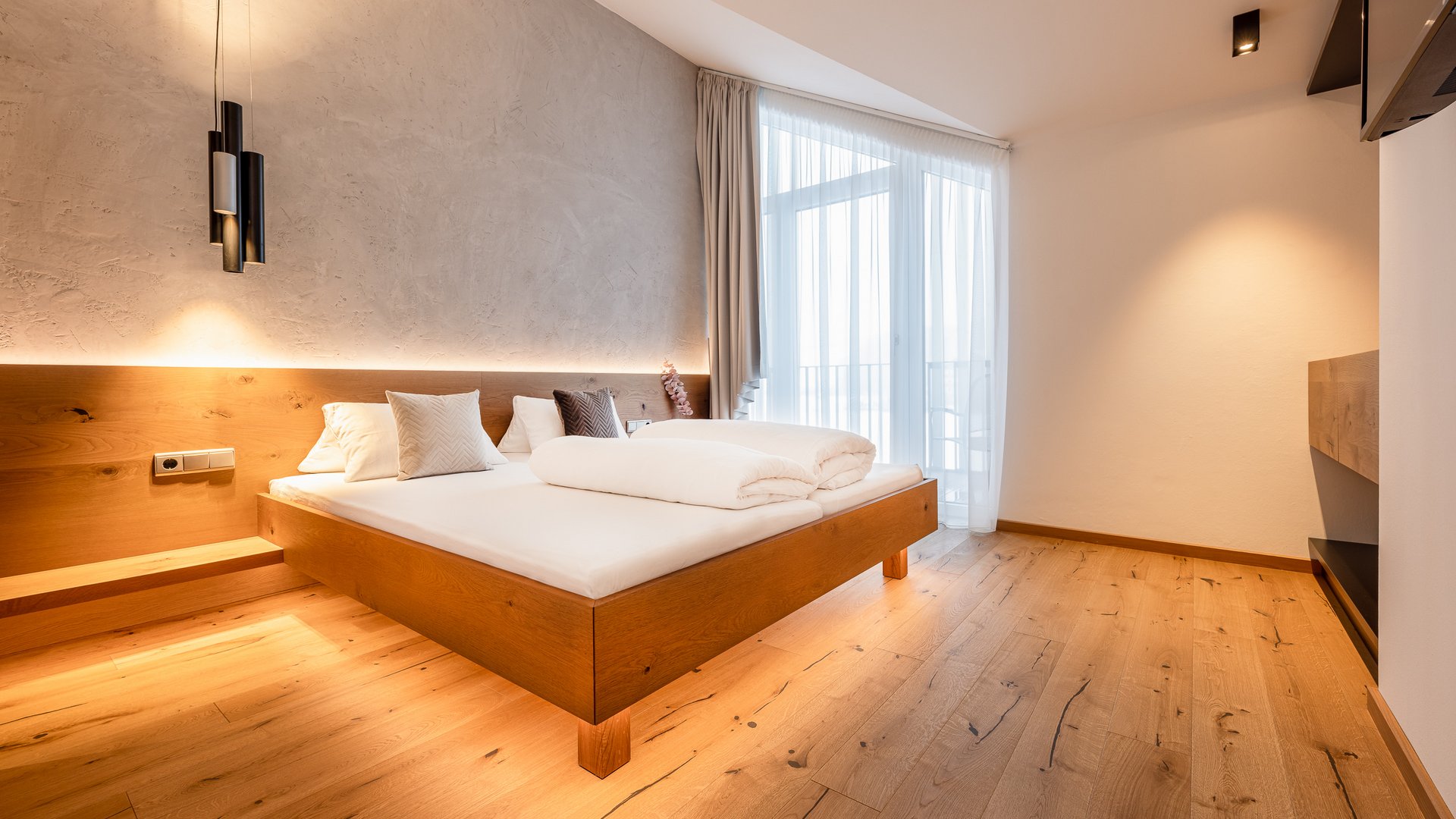 Deine Ferienwohnung in Neustift ✓ Modernes Schlafzimmer mit Holzboden und großem Bett
