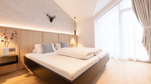 Deine Ferienwohnung in Neustift ✓ Modernes Schlafzimmer mit großem Bett, Holzboden und großem Fenster