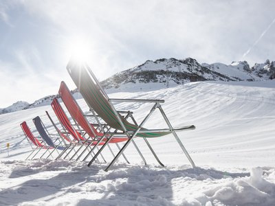Deine Ferienwohnung in Neustift ✓ Reihen von bunten Liegestühlen auf verschneitem Berg unter sonnigem Himmel