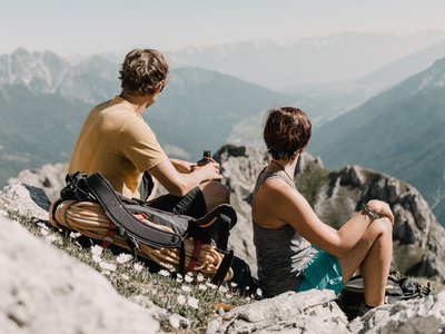 Deine Ferienwohnung in Neustift ✓ Zwei Wanderer sitzen auf einem Berg und genießen die Aussicht auf die Berge